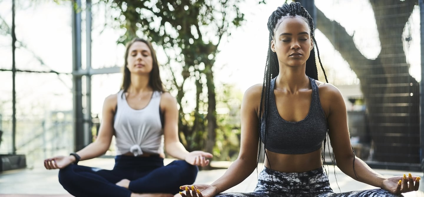 两名妇女在户外瑜伽课上静坐冥想