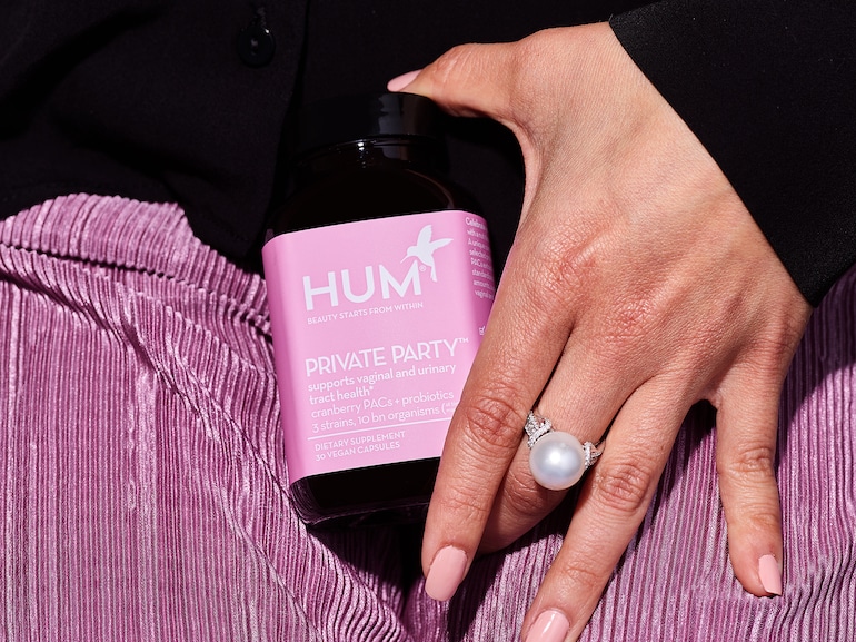 女子的手拿HUM私人派对阴道益生菌补充剂在她的紫色裙子前面