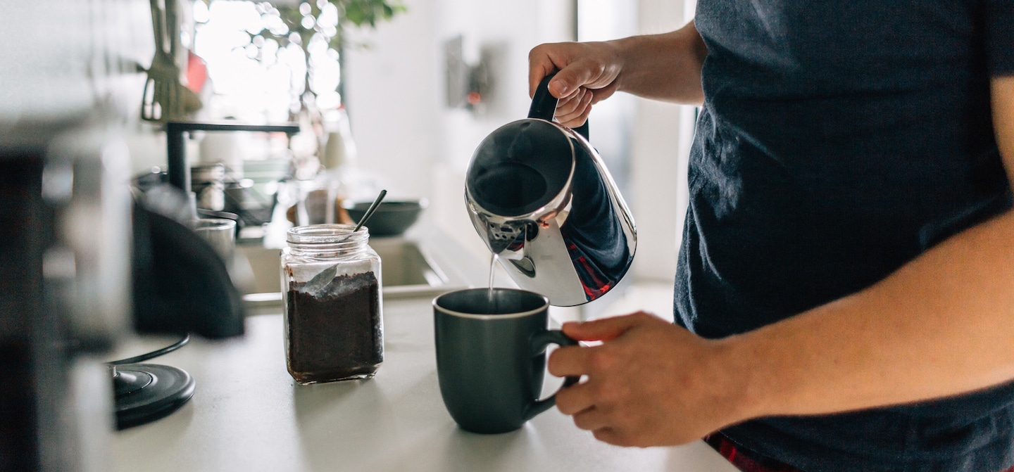 男人在家倒咖啡，但过多的咖啡因会削弱免疫功能