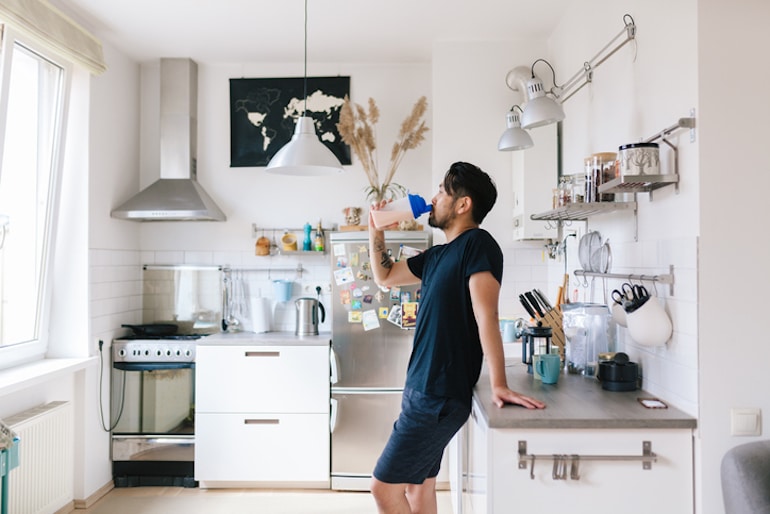 人在他的厨房喝蛋白奶昔锻炼平衡血糖,避免欲望