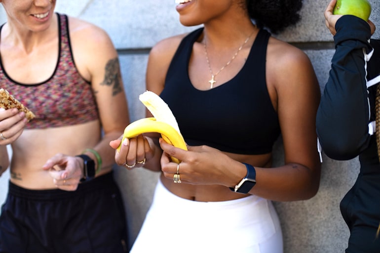 一群妇女在锻炼后，其中一个剥香蕉，因为香蕉是一种很好的能量健康食物