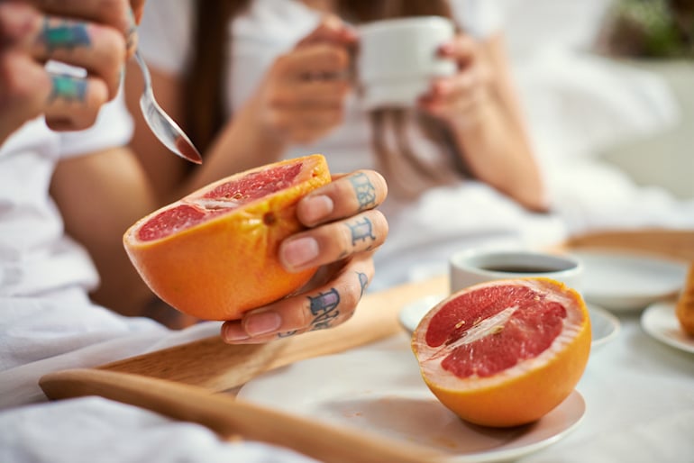 一对情侣在床上吃葡萄柚和咖啡