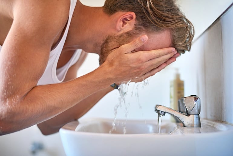 年轻男子在用乳酸去角质前先洗脸和胡子