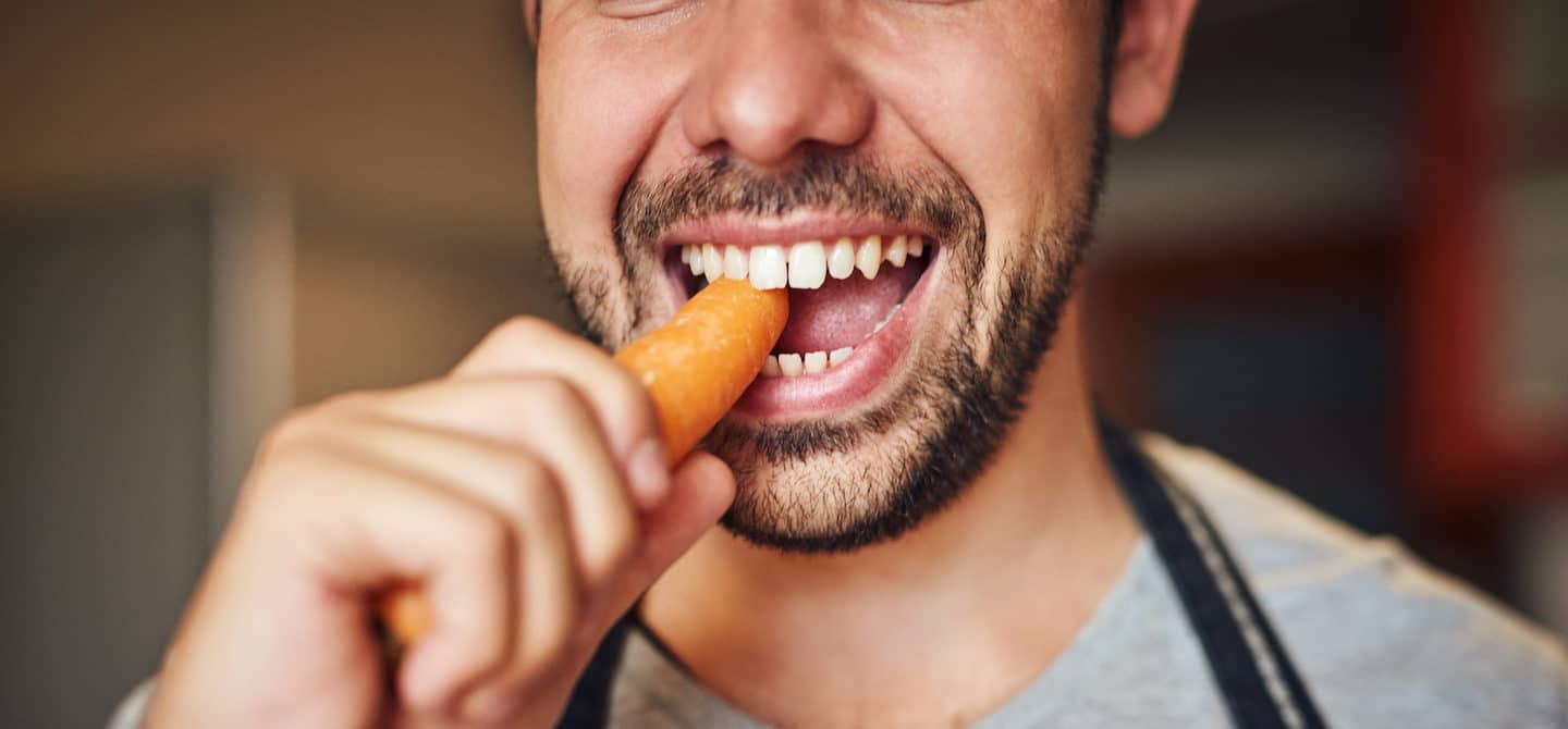 一个男人嚼着胡萝卜来说明你应该嚼多少次食物