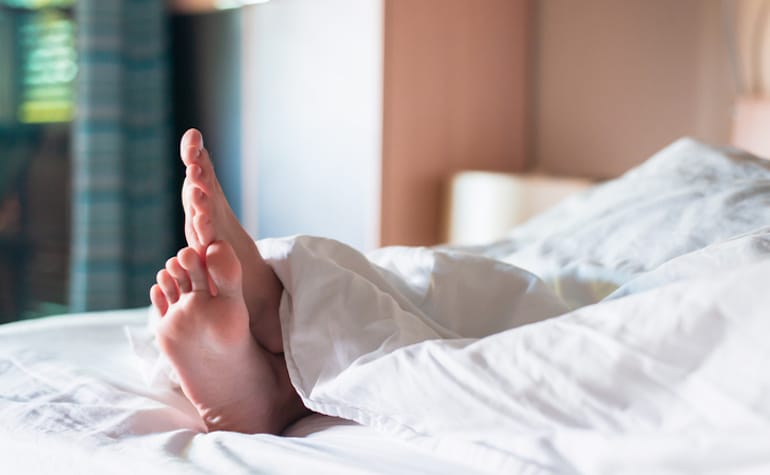 人的脚在加重的毯子下在床上获得好处的压力和睡眠