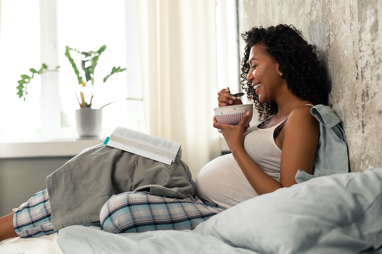 怀孕的女人在床上吃早餐,见她怀孕期间的营养需求