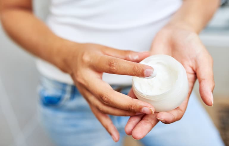 妇女拿着一个新的保湿霜，这可能会导致皮肤清洁