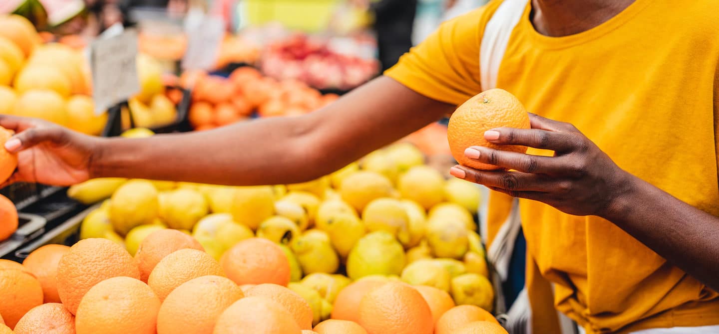 妇女在农贸市场购买柑橘类水果作为一种更可持续的饮食方法