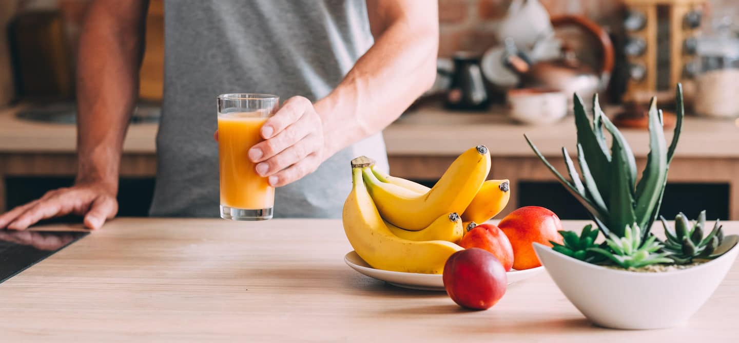 男子在厨房拿着果汁香蕉和苹果帮助减少腹胀