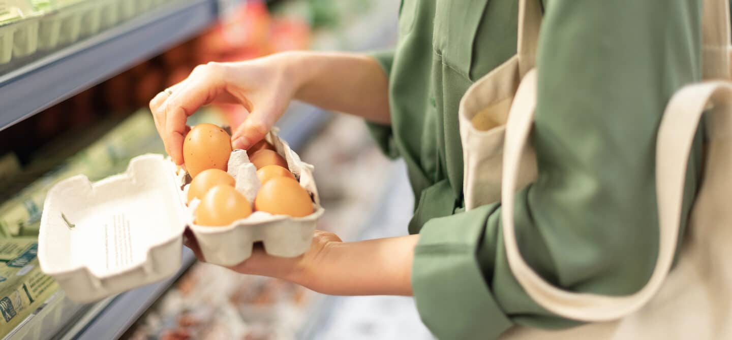 超市里的妇女拿着牧场饲养的鸡蛋，根据营养成分和价值，这是最好的鸡蛋