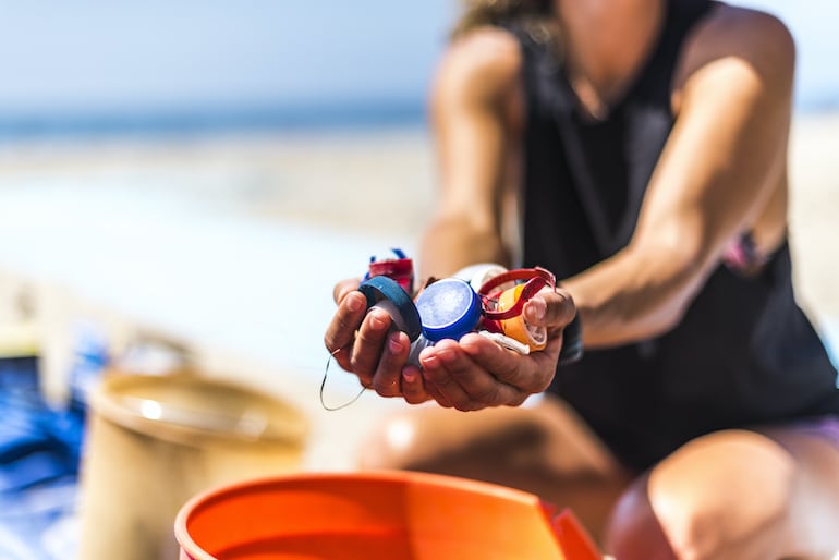 拿着瓶盖的妇女最终会成为海洋中的塑料污染物